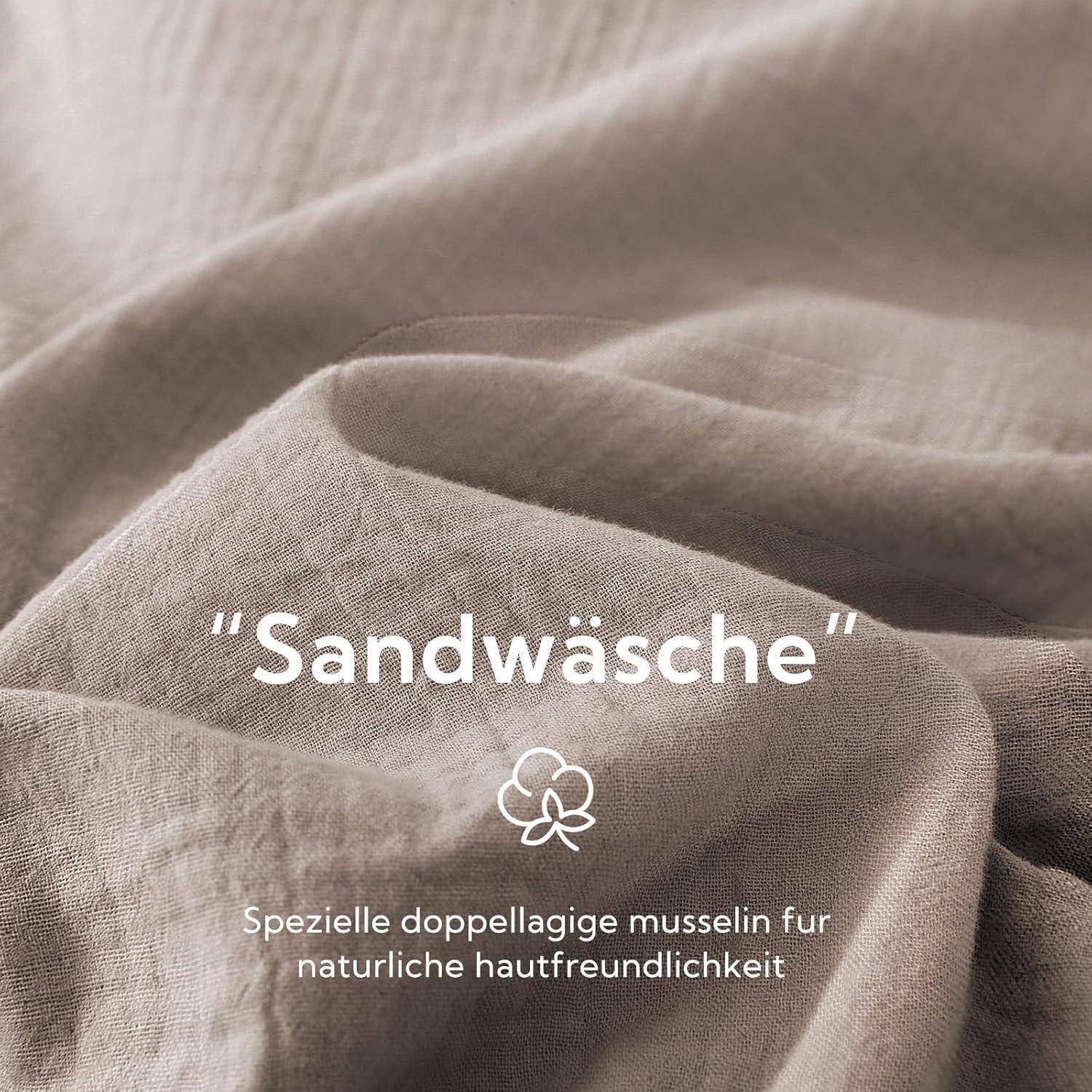 Beiger Stoff mit der Bezeichnung ‚Sandwäsche', der eine natürliche, zweischichtige Musselin-Textur aufweist, unterstreicht seine hautfreundlichen Eigenschaften.