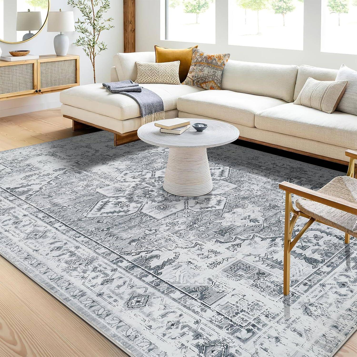 Ein modernes Wohnzimmer präsentiert ein weißes Ecksofa mit verschiedenen Kissen, einen runden Couchtisch, einen gemusterten Teppich und einen Holzstuhl.