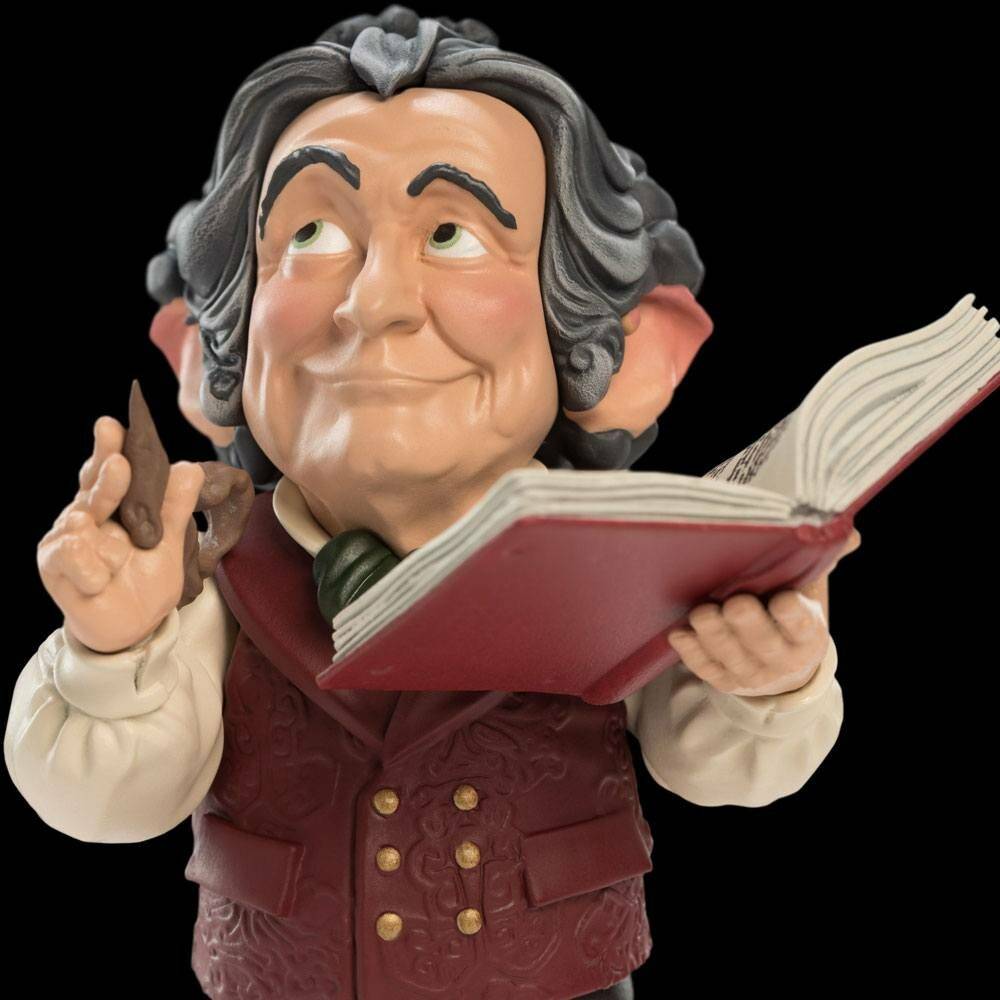 Eine Figur eines lächelnden Mannes, der ein offenes Buch mit einer Hand hält und mit der anderen gestikuliert, gekleidet in eine formelle Weste und Krawatte.