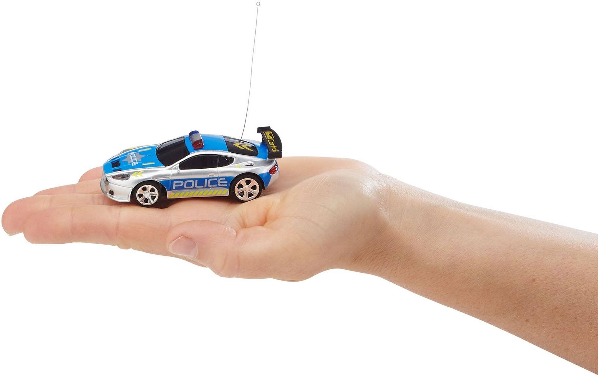 Ein blau-weißes Spielzeug-Polizeiauto mit einer Antenne ruht in einer offenen Hand und veranschaulicht seine geringe Größe.