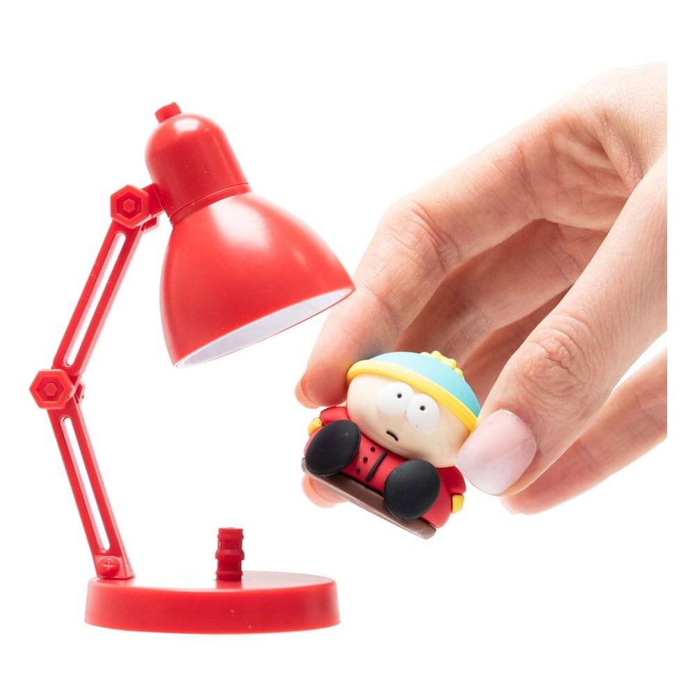 „Eine rote Schreibtischlampe neben einer Hand, die eine kleine Spielfigur hält, die einen blau-gelben Hut und eine rote Jacke trägt.