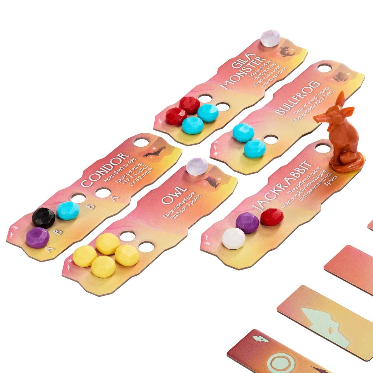 Brettspielkomponenten auf weißem Hintergrund, einschließlich Spielfiguren, Karten mit den Namen 'Gila-Kröte', 'Stierfrosch', 'Kondor', 'Eule' und 'Kaninchen', und farbcodierten Spielsteinen.