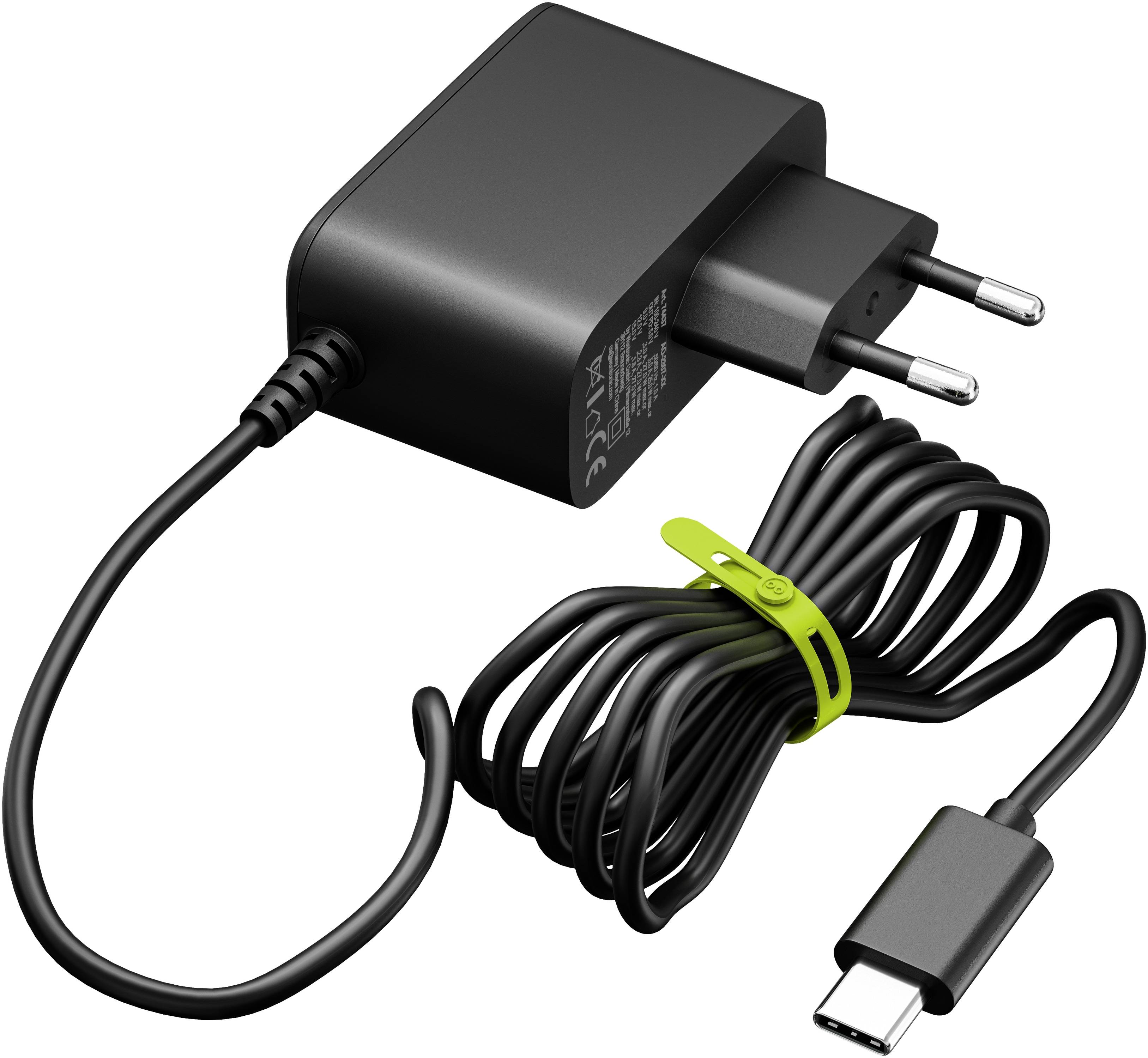 Ein schwarzes Wandladegerät mit europäischem Stecker und einem schwarzen Kabel, das in einen USB-C-Anschluss endet, aufgewickelt und mit einem grünen Klettverschluss befestigt.