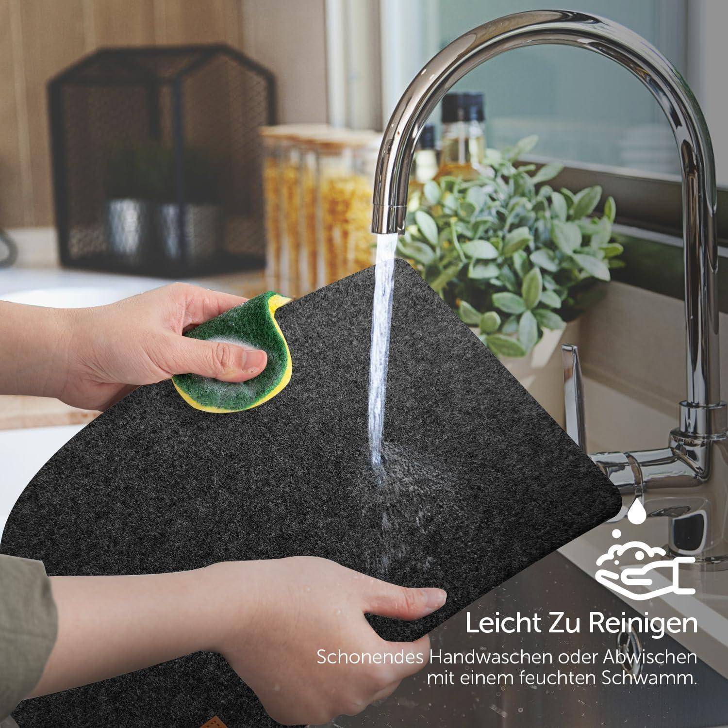 Leicht zu reinigen. Schonendes Handwaschen oder Abwischen mit einem feuchten Schwamm. Eine Person reinigt eine schwarze Oberfläche unter einem Wasserhahn.
