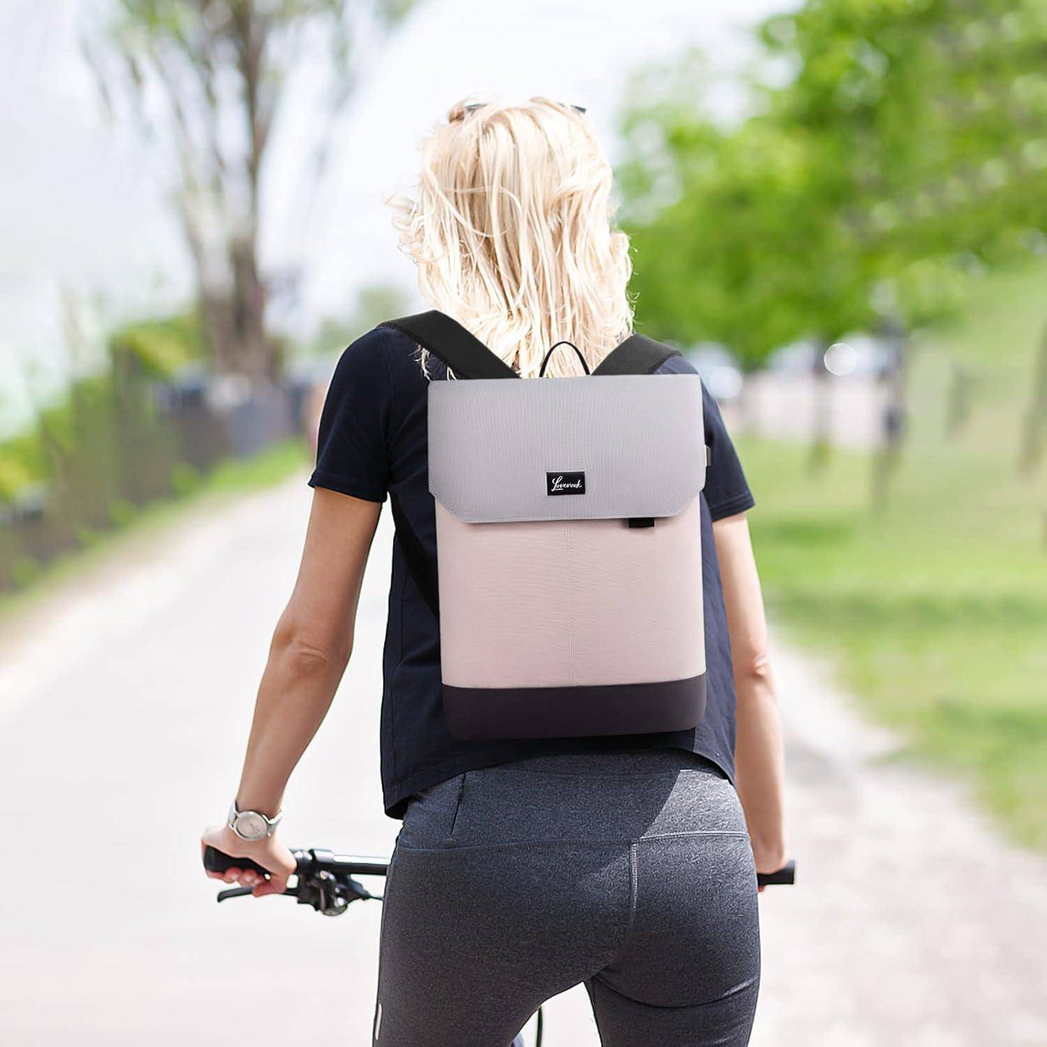 Eine Person geht auf einem Weg mit einem hellgrauen Rucksack und hält ein Telefon. Im Hintergrund befinden sich Grünpflanzen und eine unscharf wirkende Ansicht eines Weges.