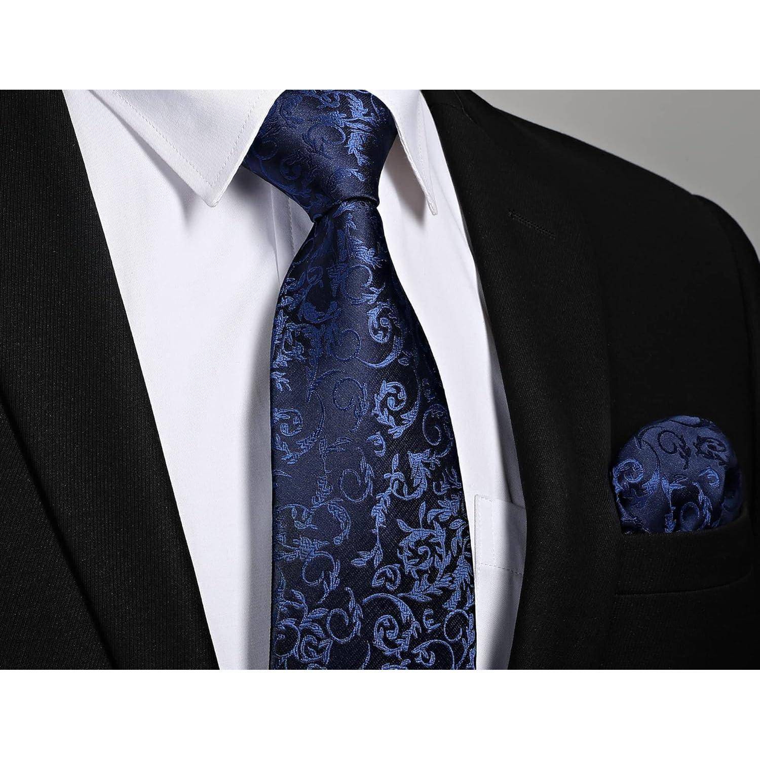 Eine Person, die einen schwarzen Anzug mit einem weißen Hemd trägt, mit einer blauen Krawatte mit Paisley-Mustern und dem passenden Einstecktuch.