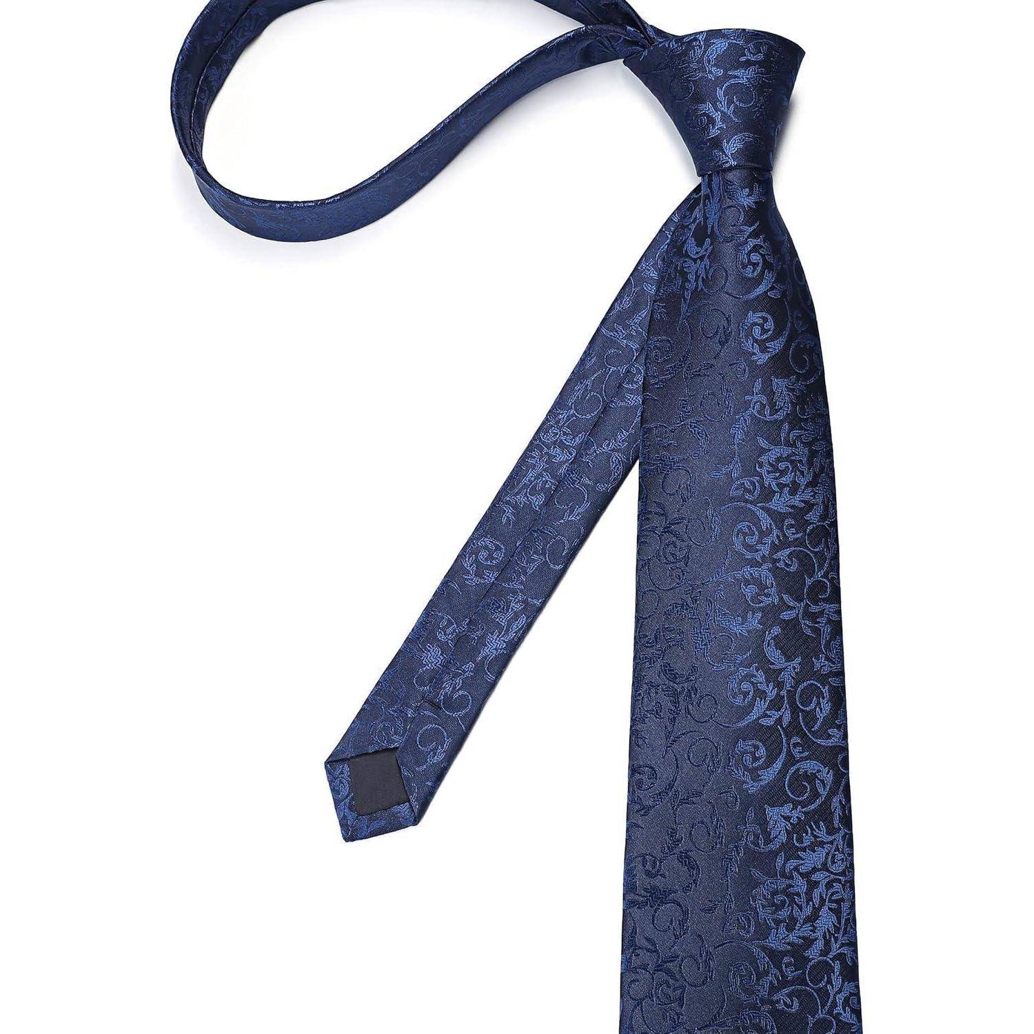 Eine blaue Krawatte mit Blumenmuster, die vor einem weißen Hintergrund präsentiert wird und das filigrane Design und die Eleganz des Stoffes hervorhebt.