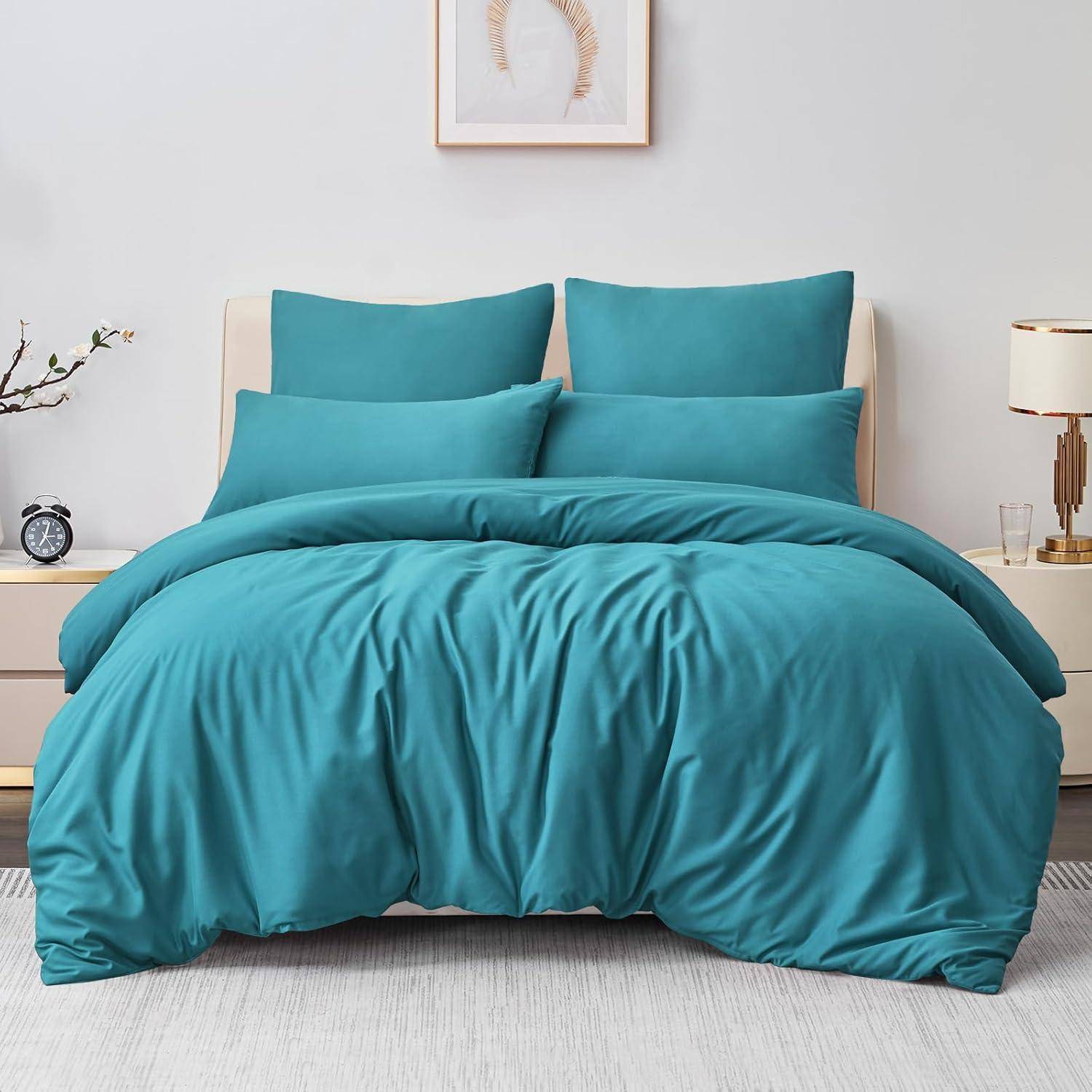 Ein ordentlich gemachtes Bett mit türkisfarbener Bettwäsche, zwei Kissen, einer Bettdecke und einem beigen Kopfteil. Ein Nachttisch trägt eine Lampe und kleine Dekorationen.