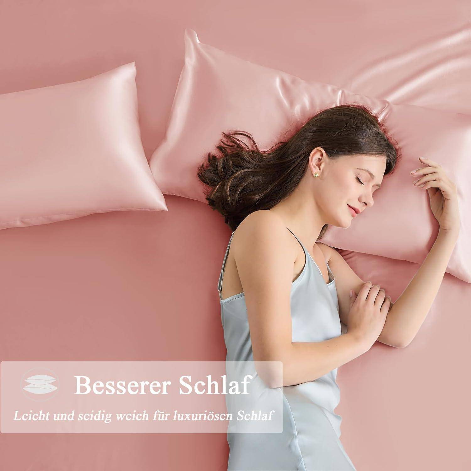 Eine Frau in einem Satinträgerkleid liegt auf einem rosa Bett mit Satinkissen. Text lautet: 'Besserer Schlaf - Leicht und seidig weich für luxuriösen Schlaf.