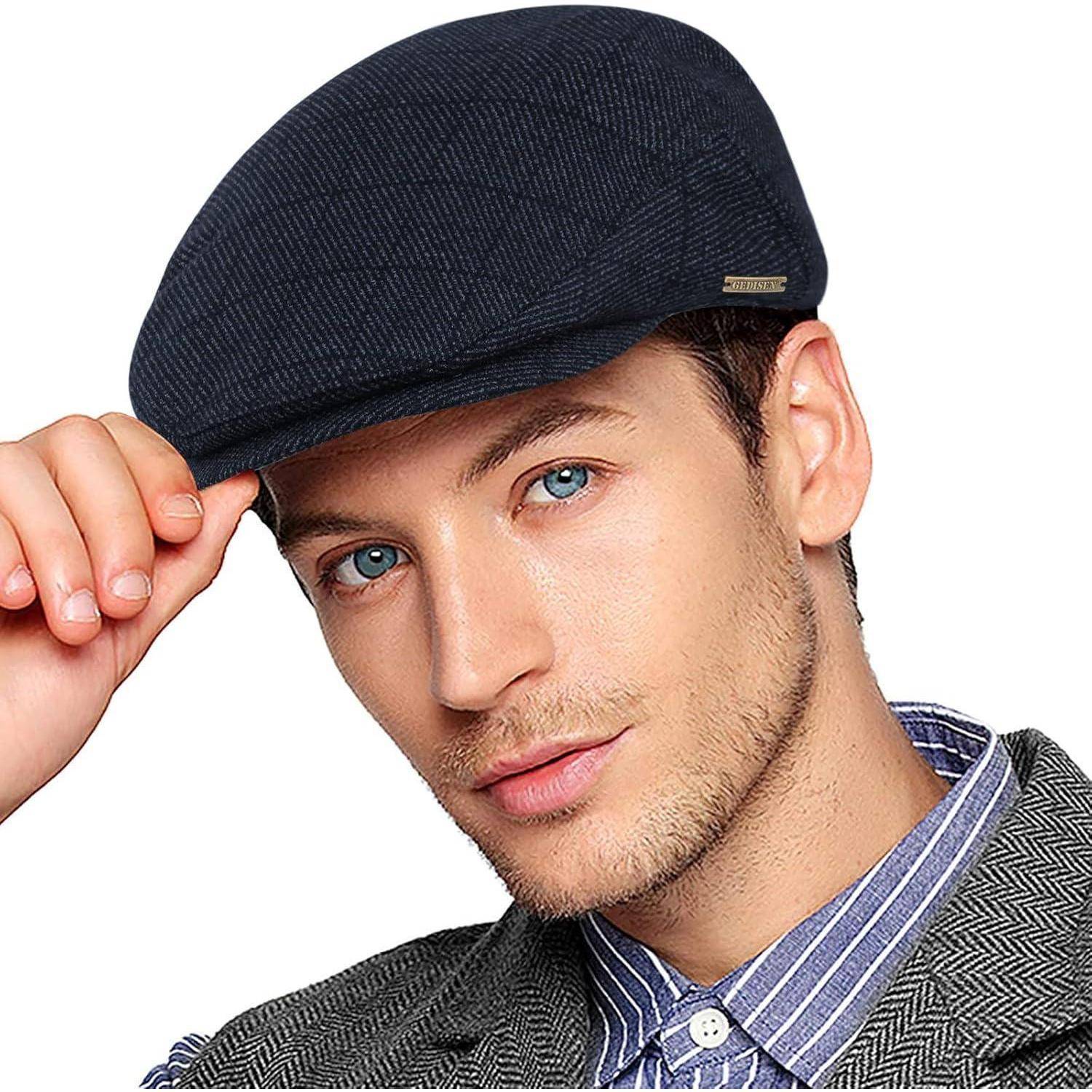 Eine Person mit einer blauen Flat Cap und einem gestreiften Hemd schaut direkt in die Kamera, mit einem leichten Lächeln und greift an den Rand der Mütze.