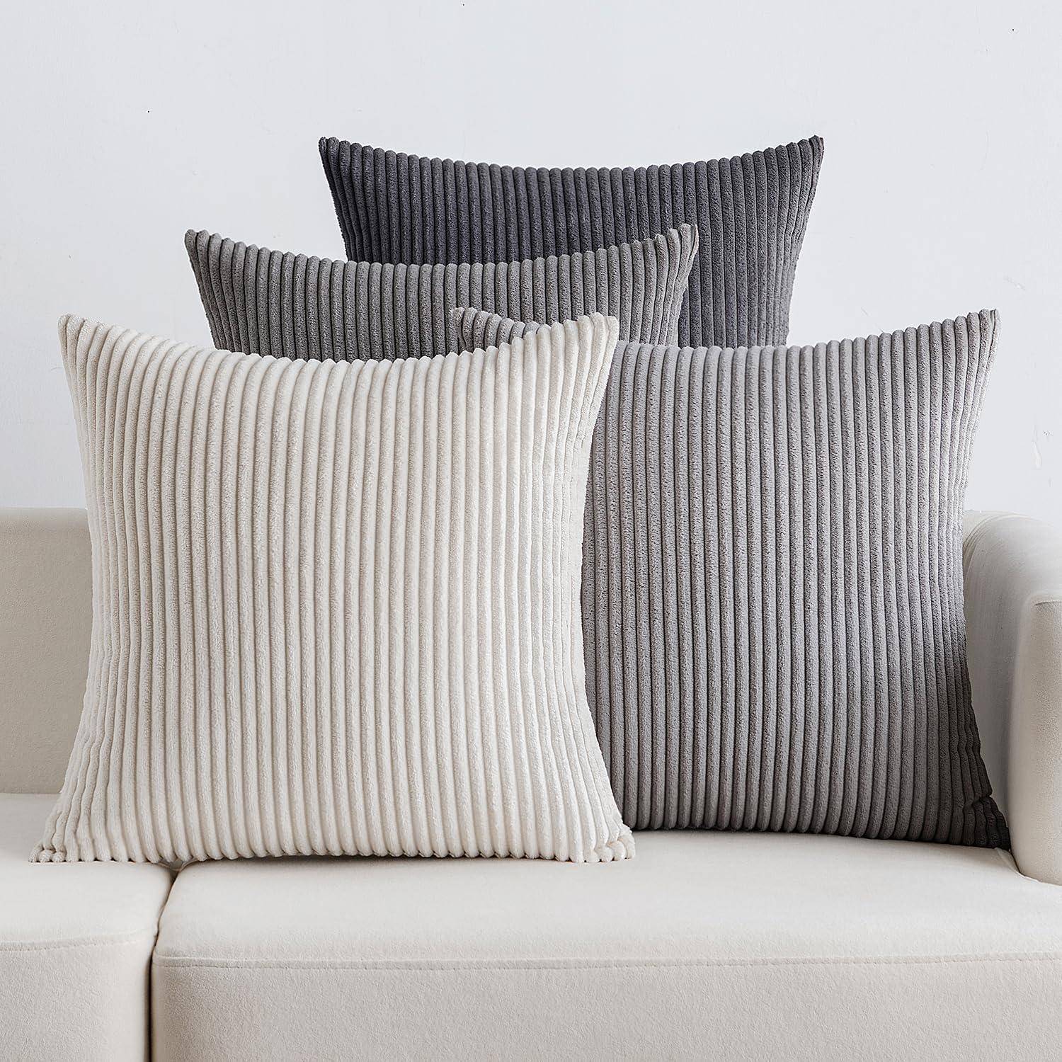 Vier gerippte Kissen in Grau- und Cremetönen, die auf einem hellgefärbten Sofa arrangiert sind und eine moderne, gemütliche Einrichtungssituation veranschaulichen.