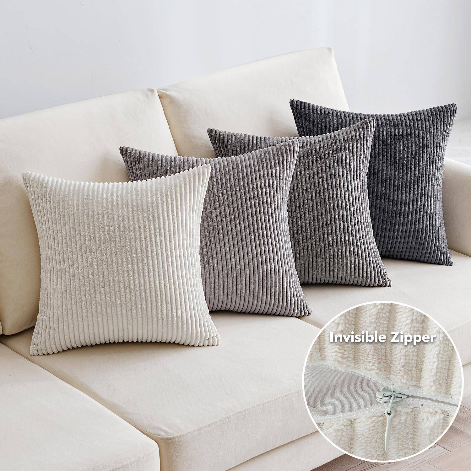 Vier gerippte Zierkissen in Beige, Hellgrau und Dunkelgrau sind auf einem cremefarbenen Sofa angeordnet. Die Detailansicht zeigt den ‚Unsichtbaren Reißverschluss'.