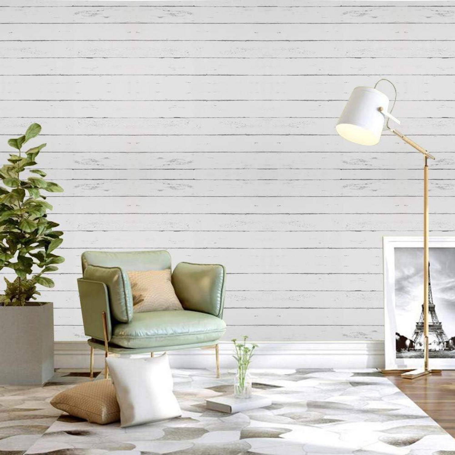 Ein gemütliches Wohnzimmer mit einem grünen Sessel, weißem Kissen, Zimmerpflanzen, einer Stehlampe und einem gerahmten Schwarz-Weiß-Foto auf dem Boden.
