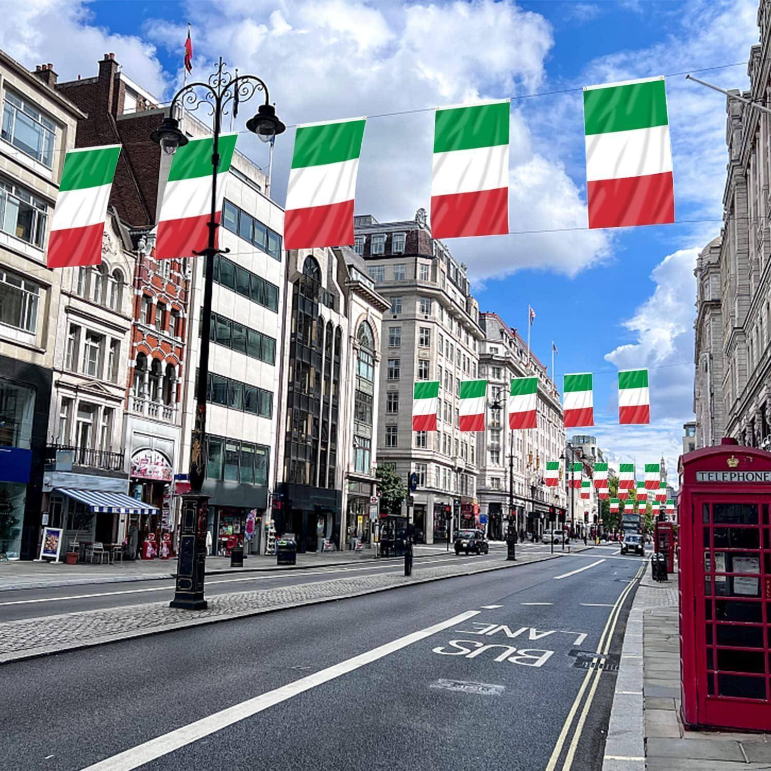Leere Stadtstraße, die mit italienischen Flaggen über der Straße geschmückt ist. Gebäude säumen die Straße, und eine rote Telefonzelle ist auf dem Gehweg zu sehen.