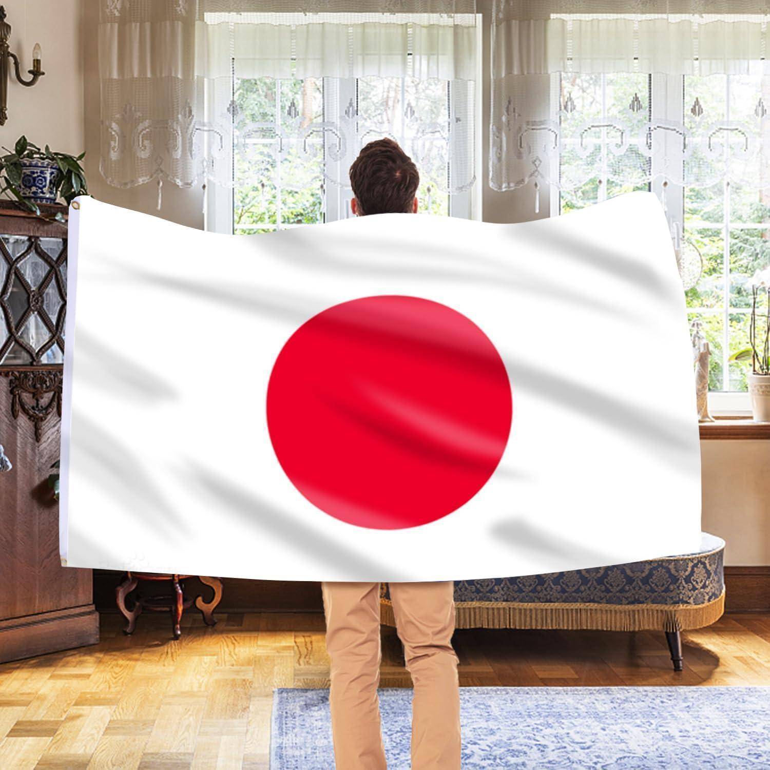 Eine Person steht drinnen und hält eine große japanische Flagge mit einem roten Kreis auf weißem Hintergrund, die teilweise ihren Rücken verdeckt.