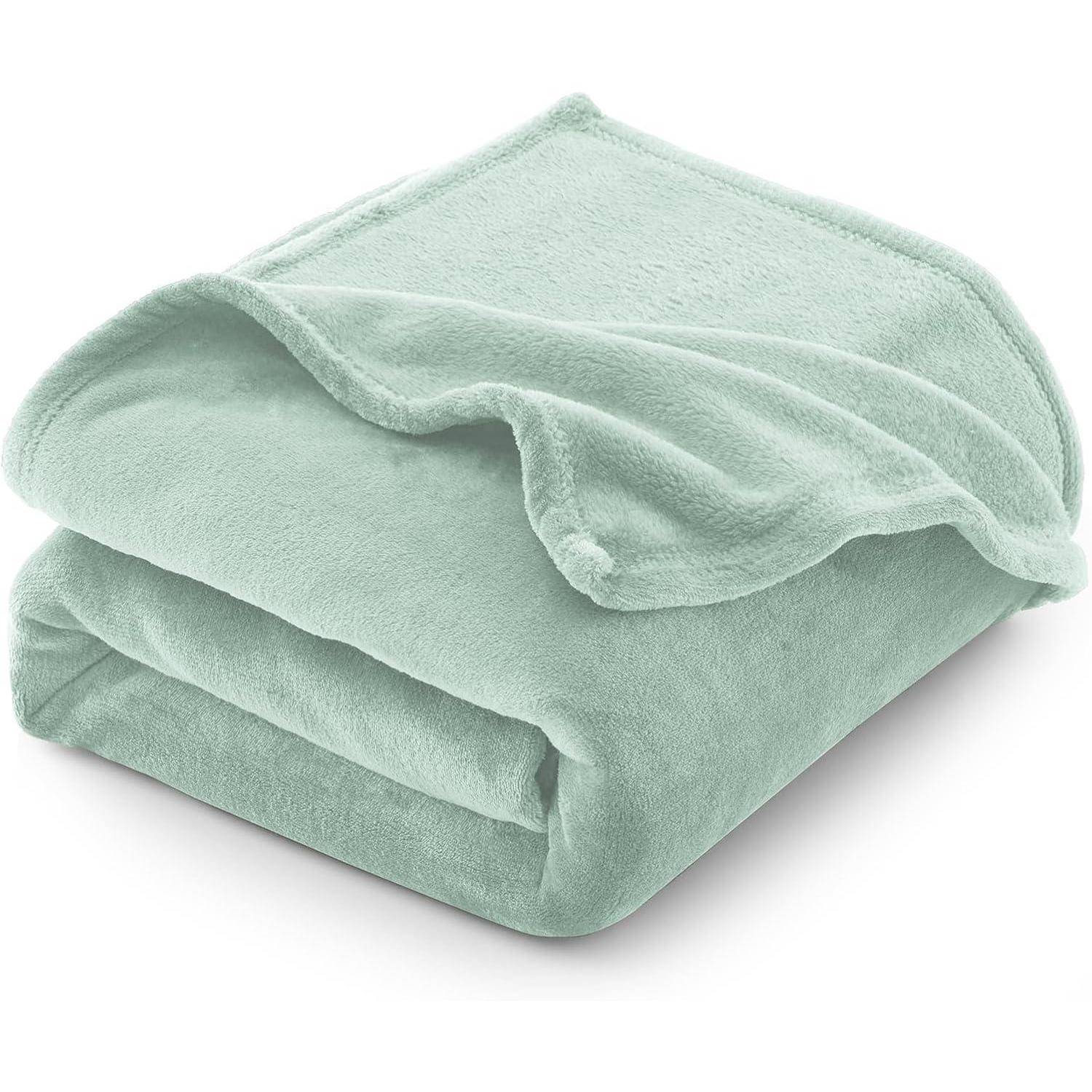 Eine weiche, gefaltete grüne Fleece-Decke auf weißem Hintergrund.