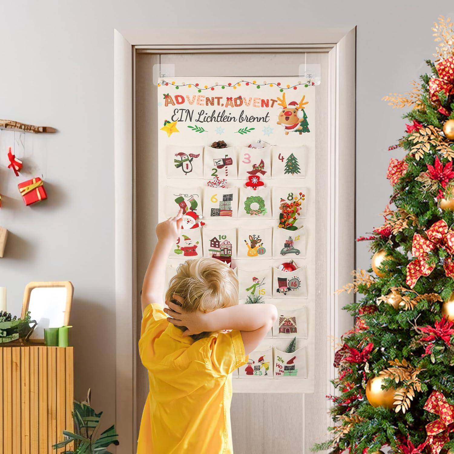 Ein Kind greift nach einem interaktiven Adventskalender, der neben einem geschmückten Weihnachtsbaum an einer Tür hängt.