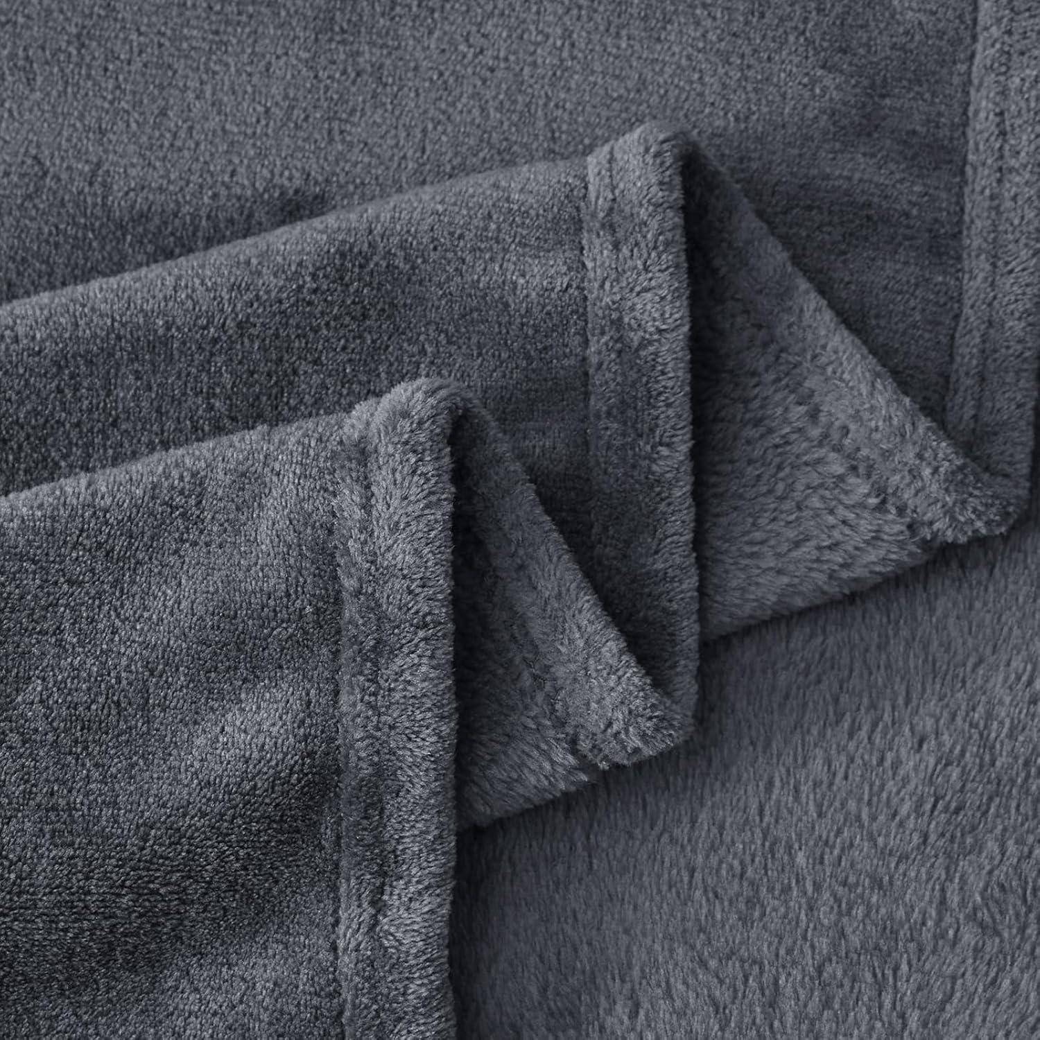 Ein Nahaufnahmebild einer weichen, grauen Fleece-Decke, die deren Textur und gefaltete Kanten zeigt.