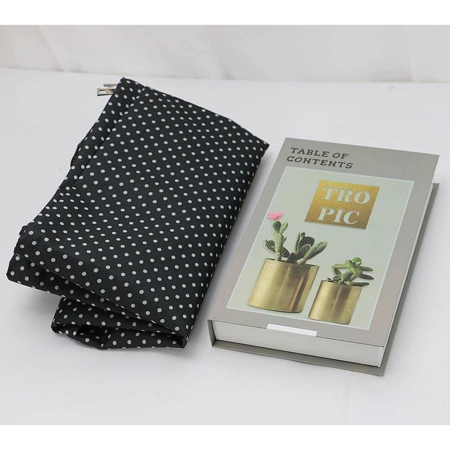 Ein schwarzer Polka-Dot-Stoff liegt gefaltet neben einem Buch mit dem Titel 