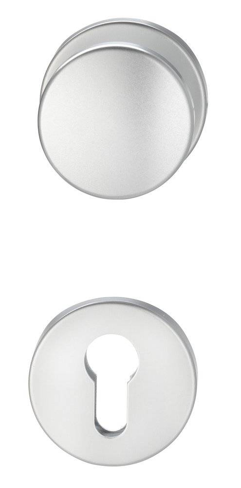 Zwei runde, metallische Ringe vor einem schlichten weißen Hintergrund. Der obere Ring ist scheibenförmig, und der untere Ring hat eine kreisförmige Öffnung in der Mitte.