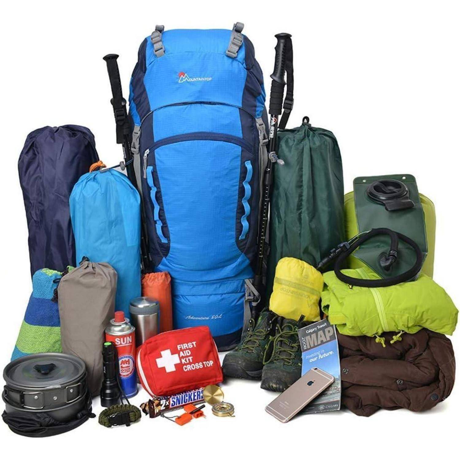 Campingausrüstung mit einem blauen Rucksack, verschiedenen Schlafsäcken, Töpfen, Wanderstiefeln, Wasserkanister, Karte, Erste-Hilfe-Set und Snacks.