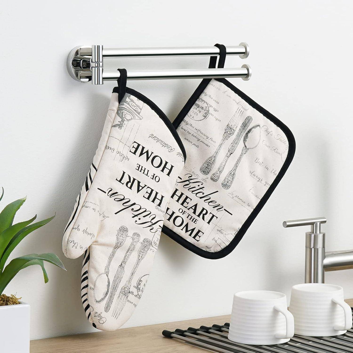 Eine Küchenszene mit einem hängenden Ofenhandschuh und einem Topflappen mit vintage Löffel- und Gabeldesigns, und dem Text ‚Herz des Hauses' darauf.