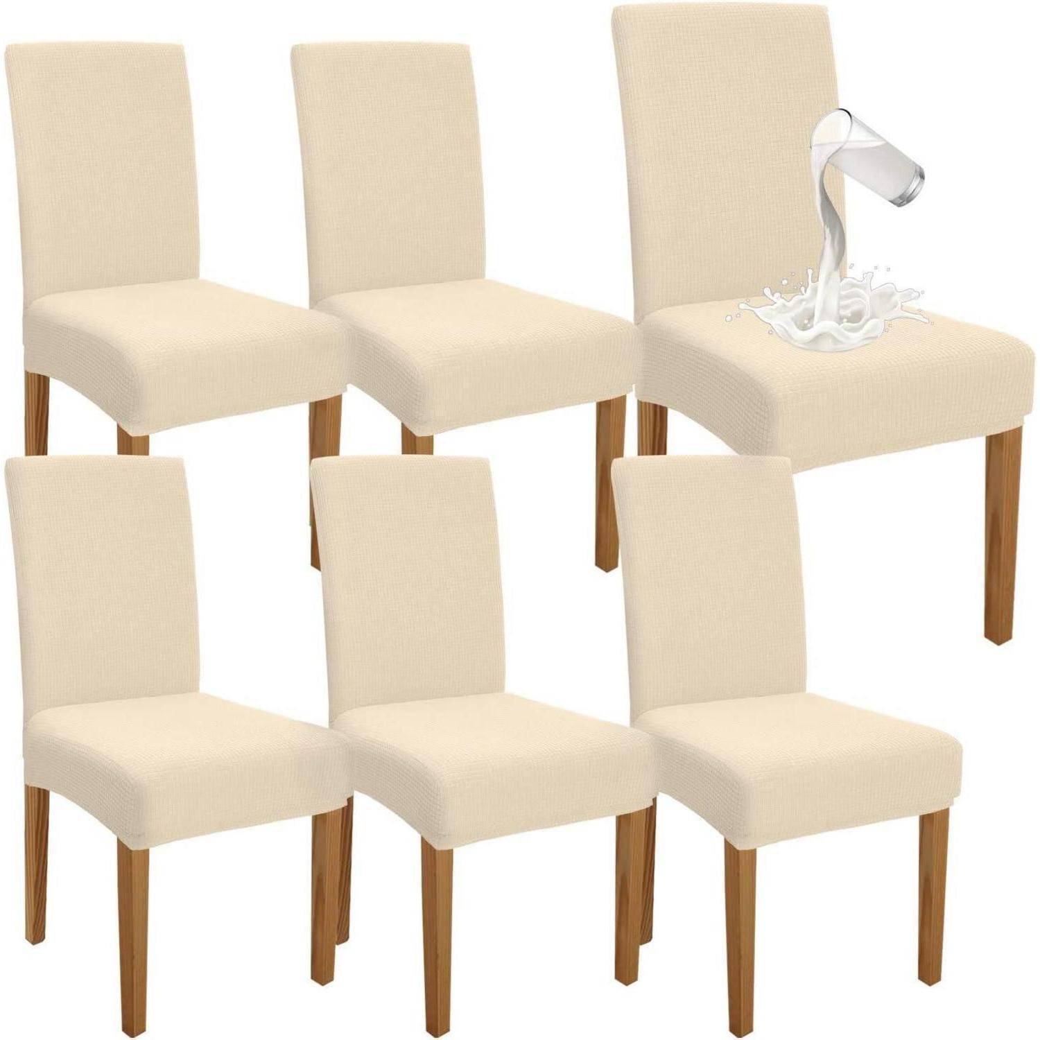 Sechs beige Essstühle mit Holzbeinen. Ein Stuhl hat ein Glas Milch, das auf den Sitz verschüttet wird.