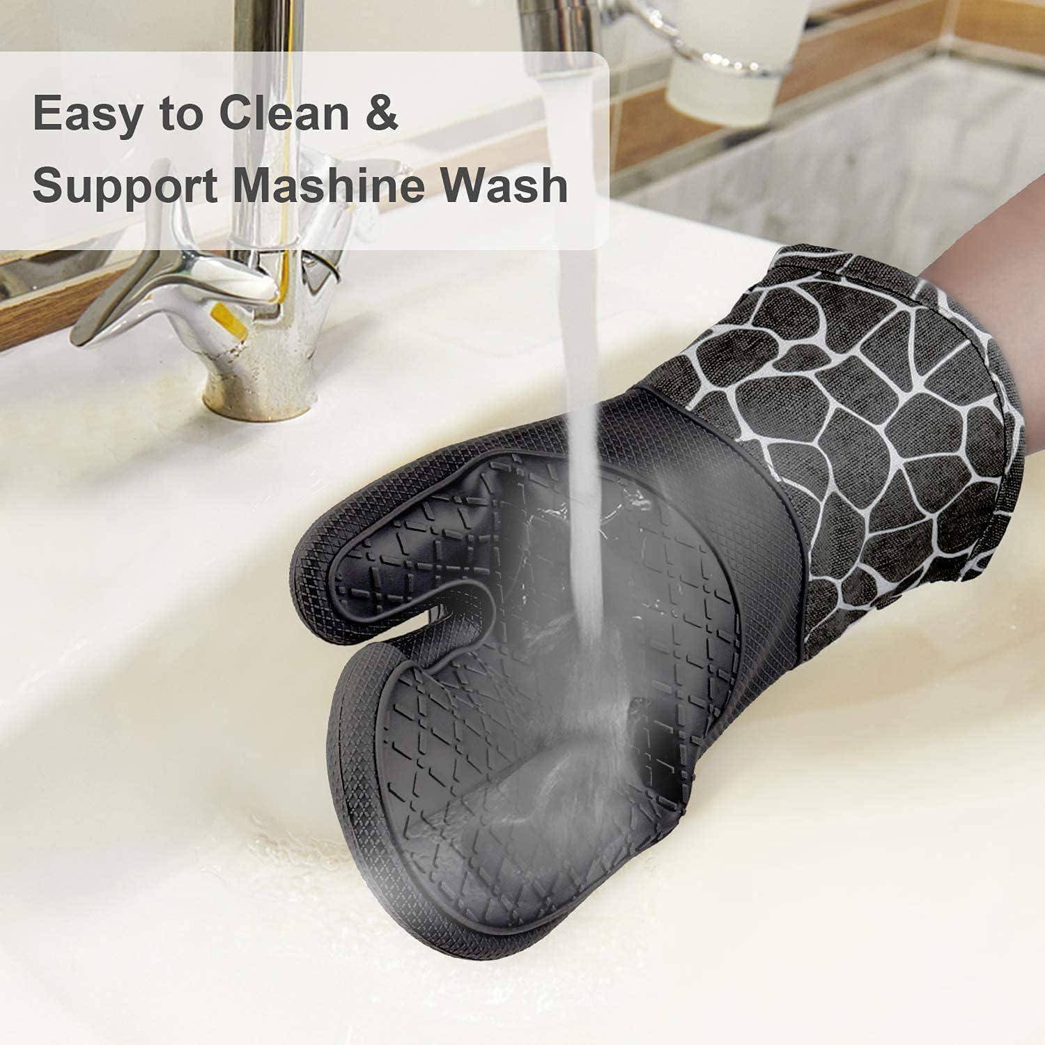 Eine Hand mit einem gemusterten Ofenhandschuh hält etwas unter fließendes Wasser in einem Waschbecken. Text lautet: „Leicht zu reinigen & maschinenwaschbar.