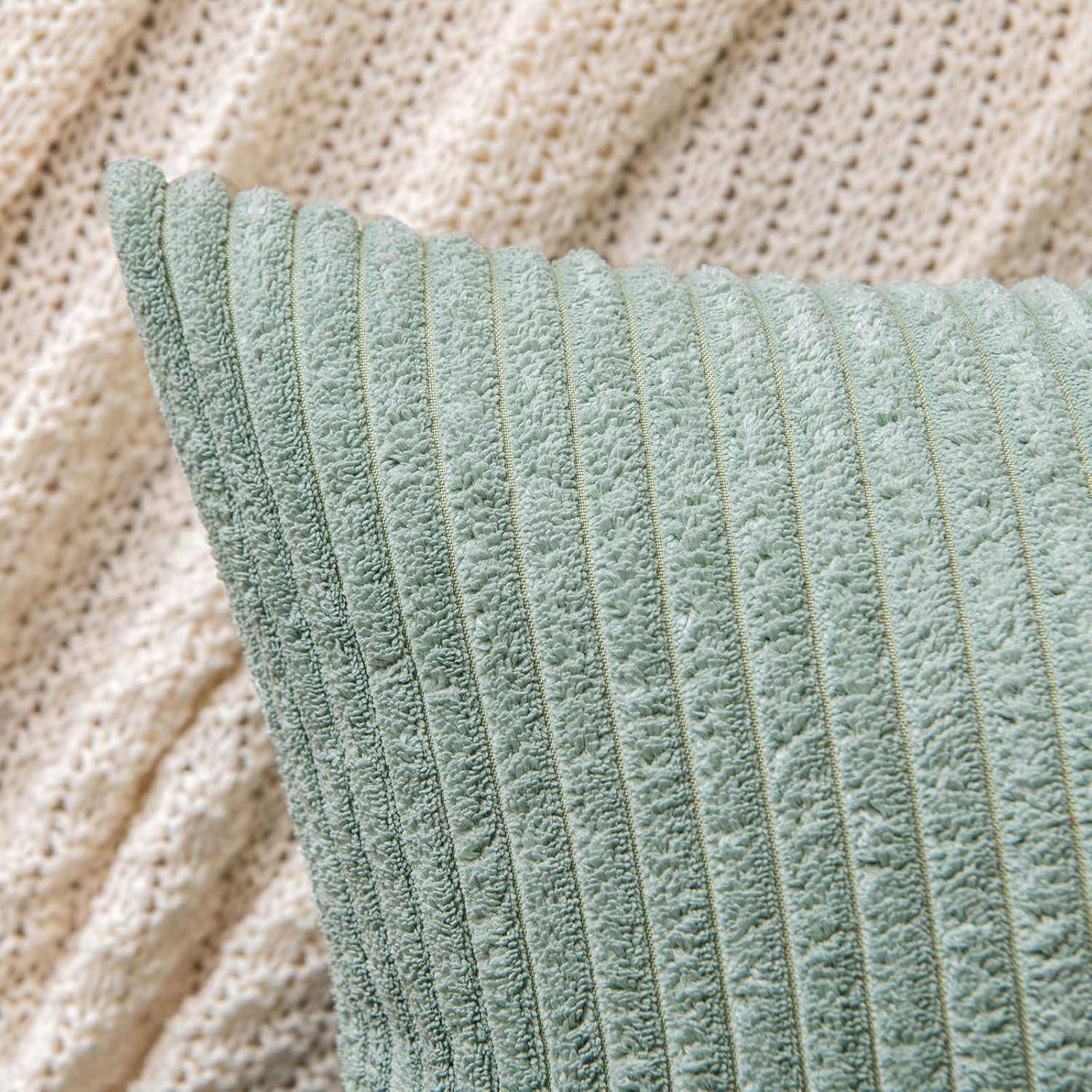 Eine Nahaufnahme eines grünen, strukturierten Kissens auf einer beigen gestrickten Decke, die die weichen und gemütlichen Materialien hervorhebt.