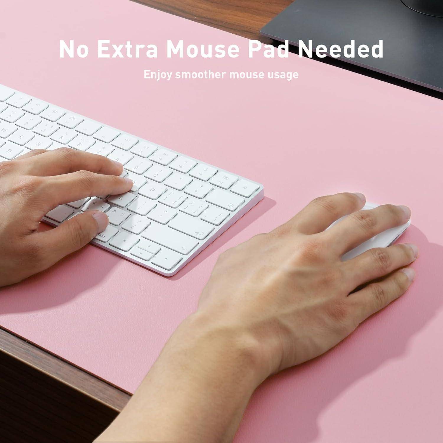 Eine Hand bedient eine Maus auf einem rosa Schreibtisch neben einer Tastatur; der Text lautet „Kein zusätzliches Mousepad nötig