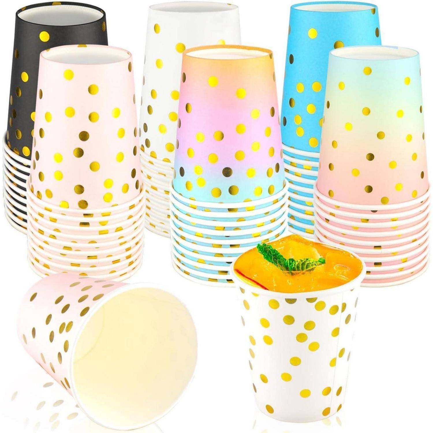 Bunte Pappbecher mit goldenen Punkten; ein Becher gefüllt mit einer Orange-Saft-Dekoration.