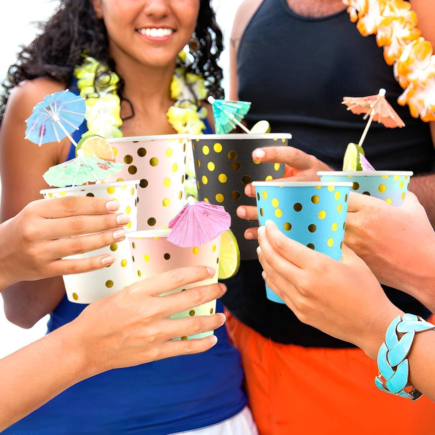Eine Gruppe von Menschen, die bunte Cocktails mit Cocktailschirmchen halten und auf einer tropisch gestalteten Party feiern.