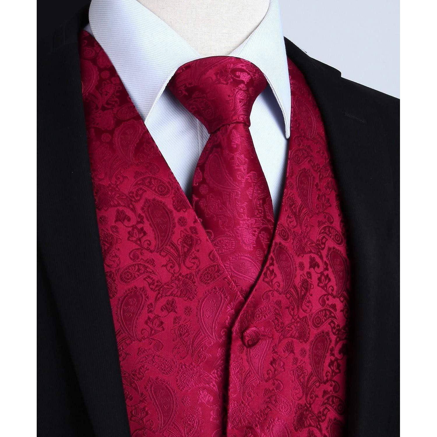 Eine Person, die einen schwarzen Anzug mit einem weißen Hemd und einer roten Paisleymuster-Krawatte und Weste trägt und damit einen formellen und eleganten Eindruck hinterlässt.
