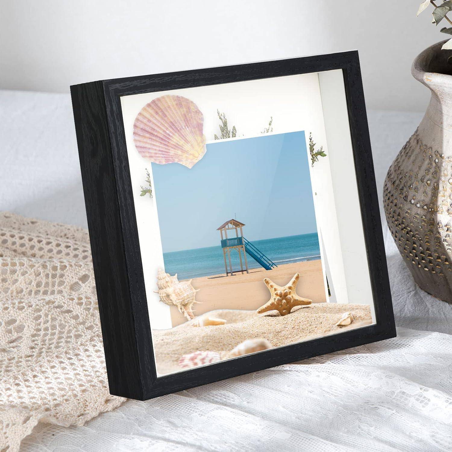 Ein gerahmtes Foto einer Strandszene mit einem Rettungsschwimmerstuhl, Meereswellen und einem sandigen Strand, dekoriert mit Muscheln und Seesternen.