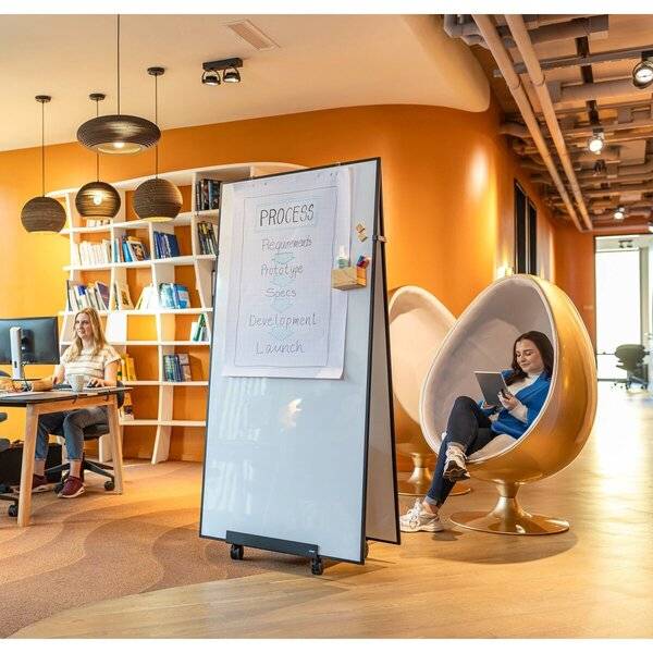 Modernes Großraumbüro mit zwei Frauen, die arbeiten, ein Whiteboard mit der Beschriftung „PROZESS