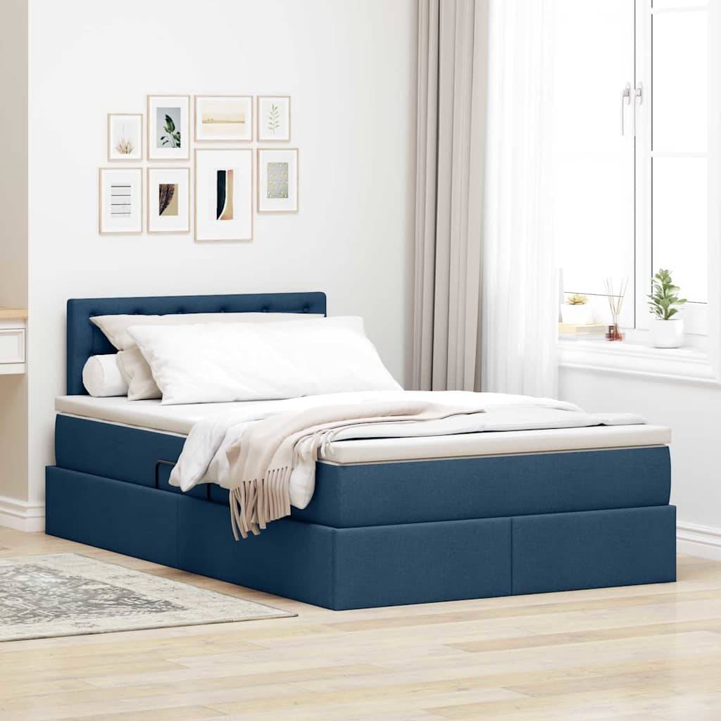 Ein Schlafzimmer mit einem blau gepolsterten Bett, weißer Bettwäsche und einer beigen Wurfdecke. Ein heller Holzboden, Wandkunst und ein Fenster mit Pflanzen verleihen dem Raum Dekoration.