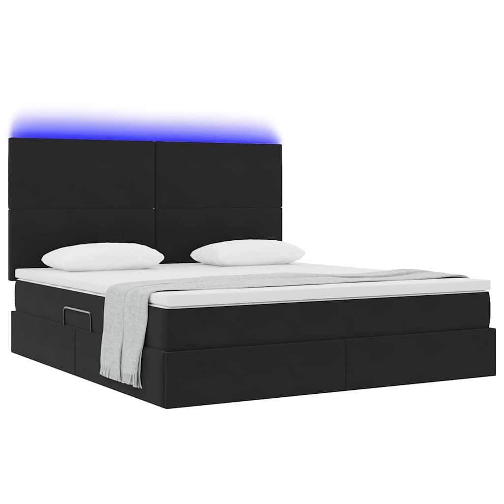 Ein modernes schwarzes Bettgestell mit beleuchtetem Kopfteil und weißer Bettwäsche, mit zwei Kissen und einer gefalteten grauen Decke am Fußende.