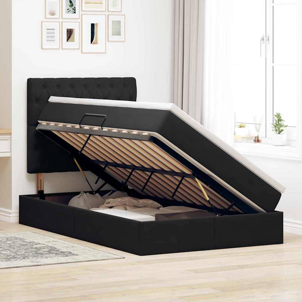Ein Bett mit angehobener Matratze zeigt darunter einen Stauraum. Es befindet sich in einem hellen Zimmer mit einem schwarzen Kopfteil und dekorativen Rahmen an der Wand.