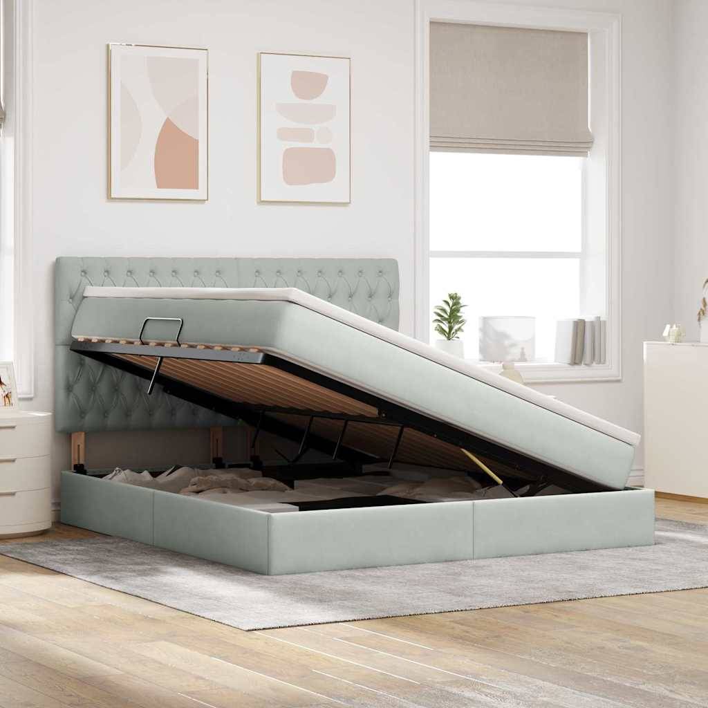 Ein hellgraues gepolstertes Bett mit Stauraum, bei dem die Matratze angehoben ist und reichlich Platz darunter sichtbar ist. Die minimalistische Schlafzimmereinrichtung umfasst abstrakte Kunst und eine Topfpflanze.