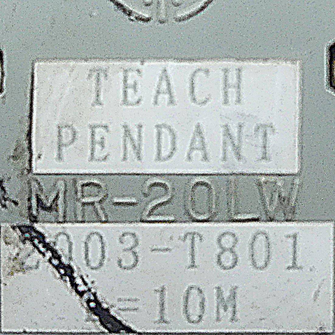 TEACH PENDANT MR-20LW 003-T801 =10M' ist auf einer Metalloberfläche eingraviert, möglicherweise Teil einer Maschine oder industriellen Ausrüstung.