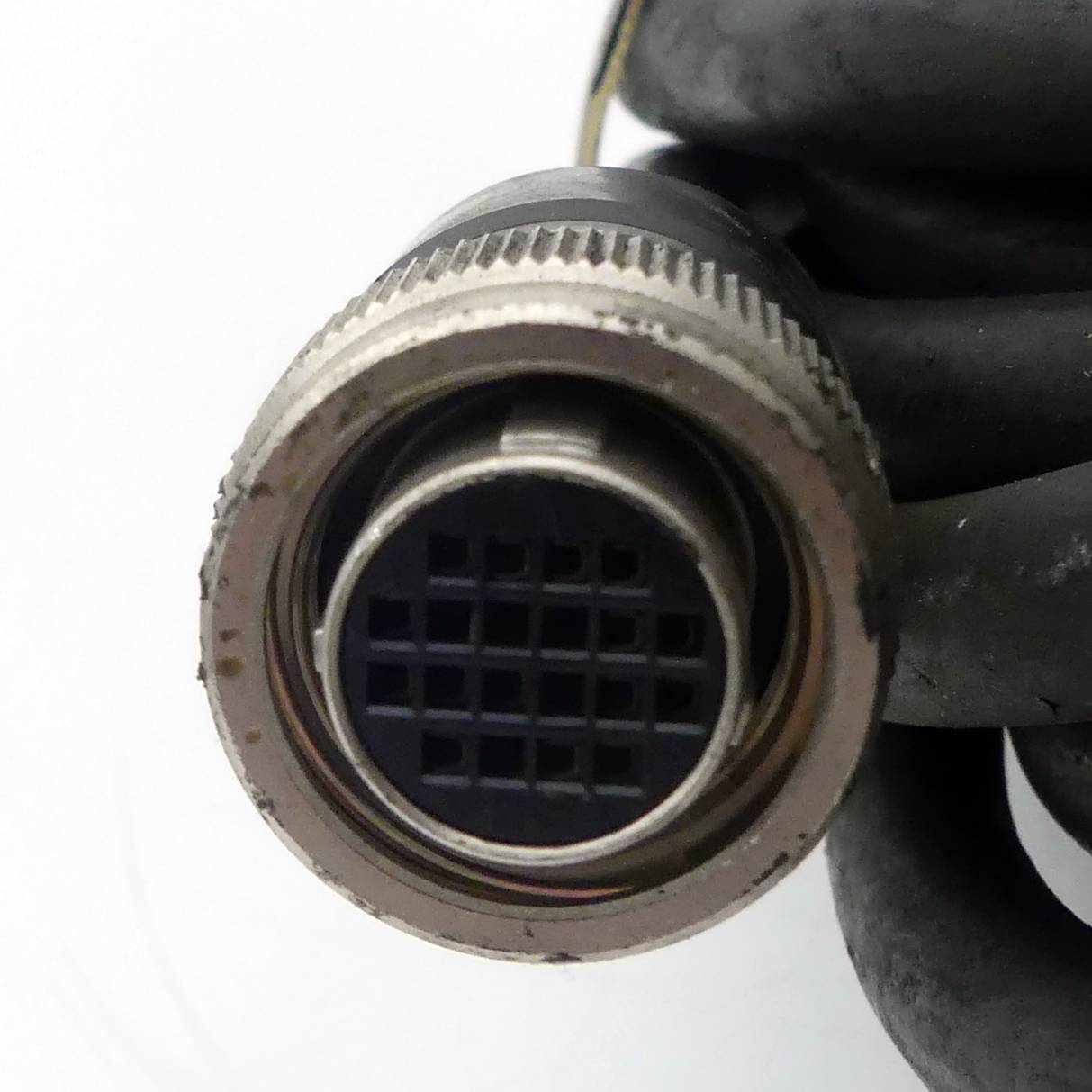 Eine Nahaufnahme eines mehrstiftigen elektronischen Kabelsteckers, der die kreisförmige Anordnung der Stifte zeigt. Das Kabel ist um ihn gewickelt.