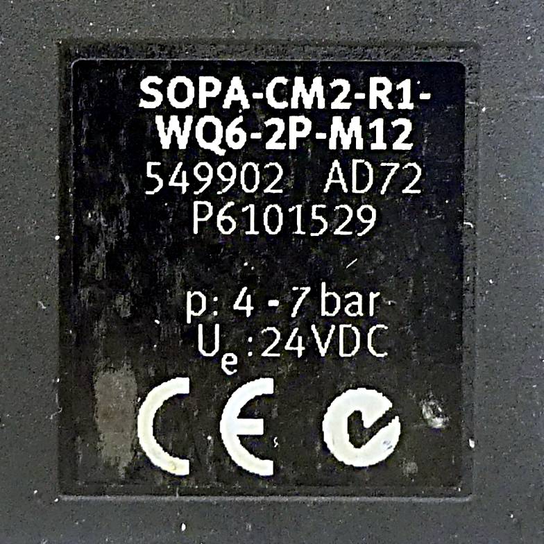 Ein schwarzes Etikett zeigt 'SOPA-CM2-R1-WQ6-2P-M12' und weitere Spezifikationen wie Druck '4-7 bar' und Spannung '24 VDC' mit Zertifizierungssymbolen.