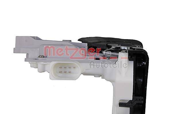Ein weißer Türschlossstellmotor mit sichtbaren elektrischen Anschlussports, beschriftet mit 'Metzger Autoteile' in roter Schrift.