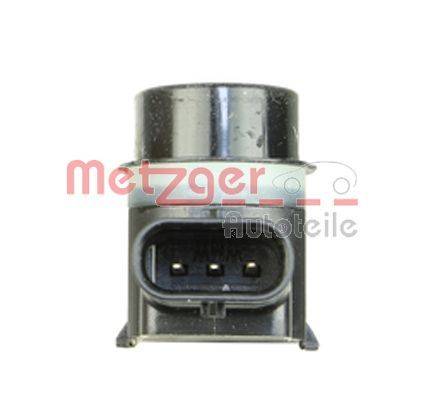 Ein schwarzer Automobielsensor mit einer kreisförmigen Oberseite und einem dreiadrigen elektrischen Anschluss an der Basis, vor einem weißen Hintergrund positioniert.