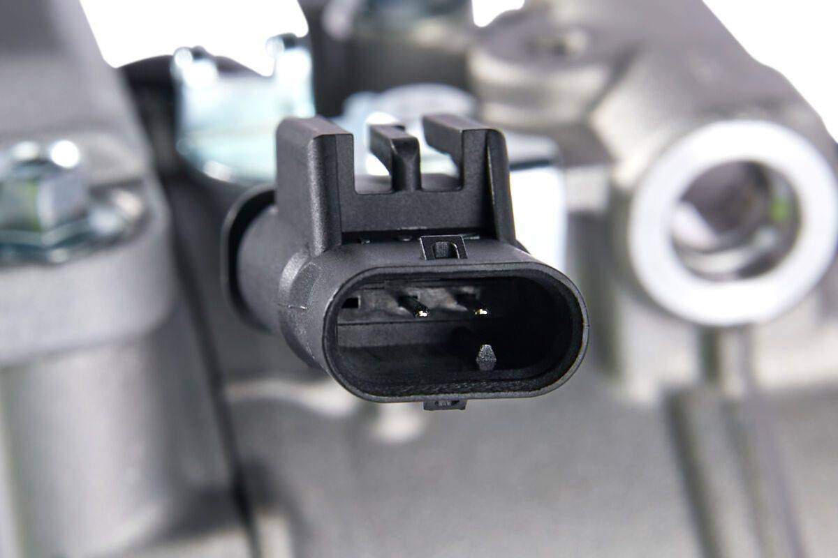 Eine Nahaufnahme eines schwarzen elektrischen Anschlusses in einem industriellen oder automobilen Umfeld, die dessen Anschlüsse und umgebende Metallkomponenten zeigt.