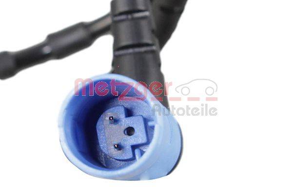 Nahaufnahme eines schwarzen Automotive-Sensorsteckers mit einem blauen Stecker, beschriftet mit 'Metzger Autoteile' in roter Schrift, die über dem Bild überlagert ist.