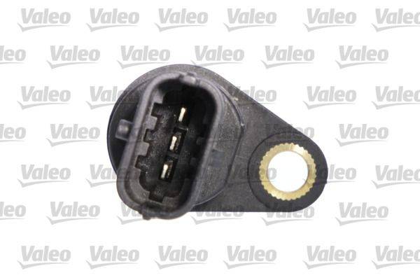Eine Nahaufnahme eines schwarzen elektronischen Sensors mit einem Mehrfachanschluss und einer einzelnen Befestigungsbohrung, vor einem Hintergrund mit sich wiederholendem 'Valeo' Logo.