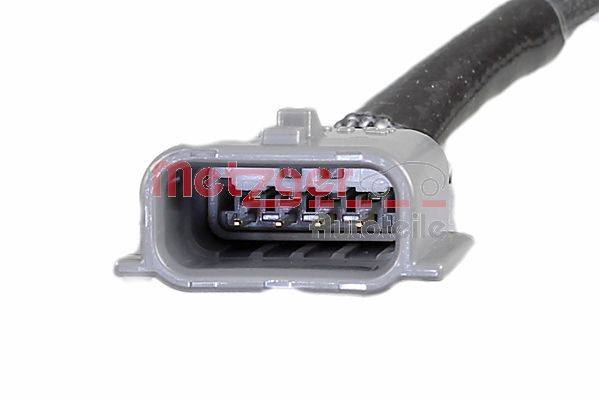 Eine Nahaufnahme eines grauen automotive Elektrosteckers mit fünf innenliegenden Kontaktstiften, angeschlossen an ein schwarzes Kabel, auf dem die Markenbezeichnung 