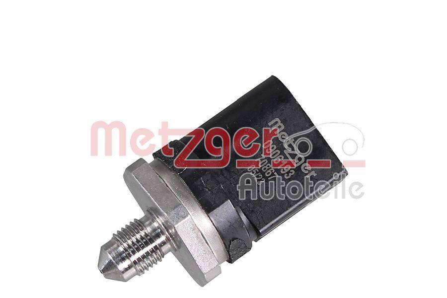 Ein metallischer Sensor mit Gewindespitze und angeschlossenem schwarzen Stecker. Der Text 'metzger Autoteile' ist teilweise sichtbar und deutet auf eine Markierung hin.