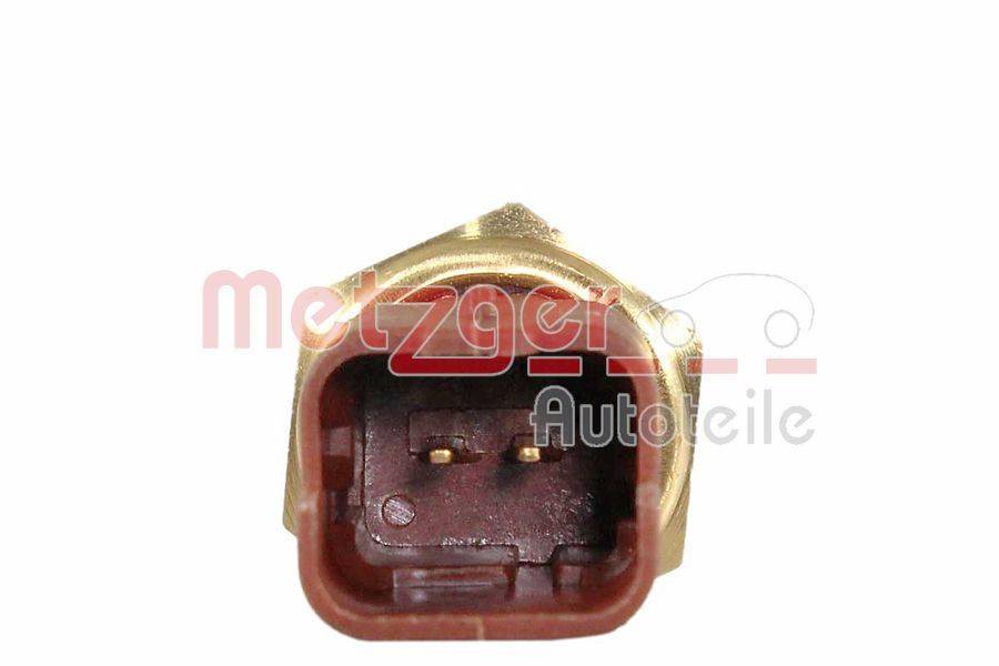 Ein Kraftstoffeinspritzer-Anschluss mit zwei sichtbaren elektrischen Pins im Inneren der Buchse, umgeben von einem goldenen Metallgehäuse.